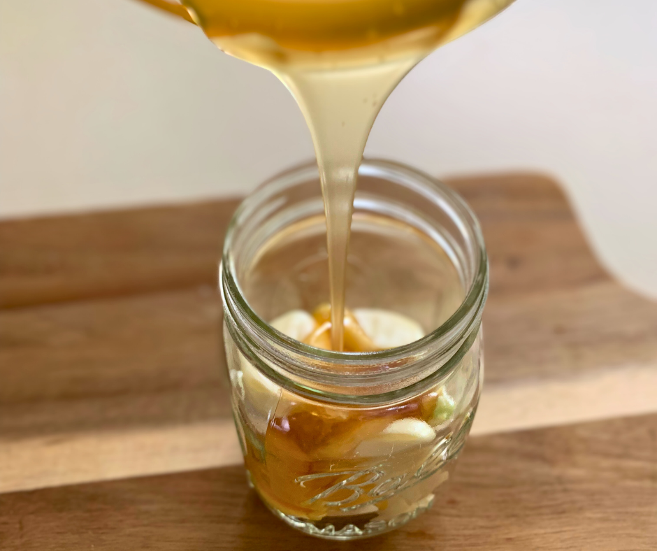 photo of pouring honey over garlic in a jar