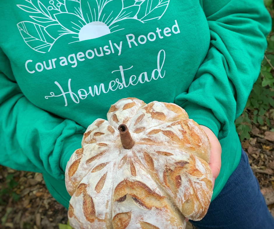 a photo of woman holding a pumpkin sourdough loaf